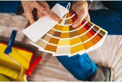 person's hands holding a fan deck of paint color swatches