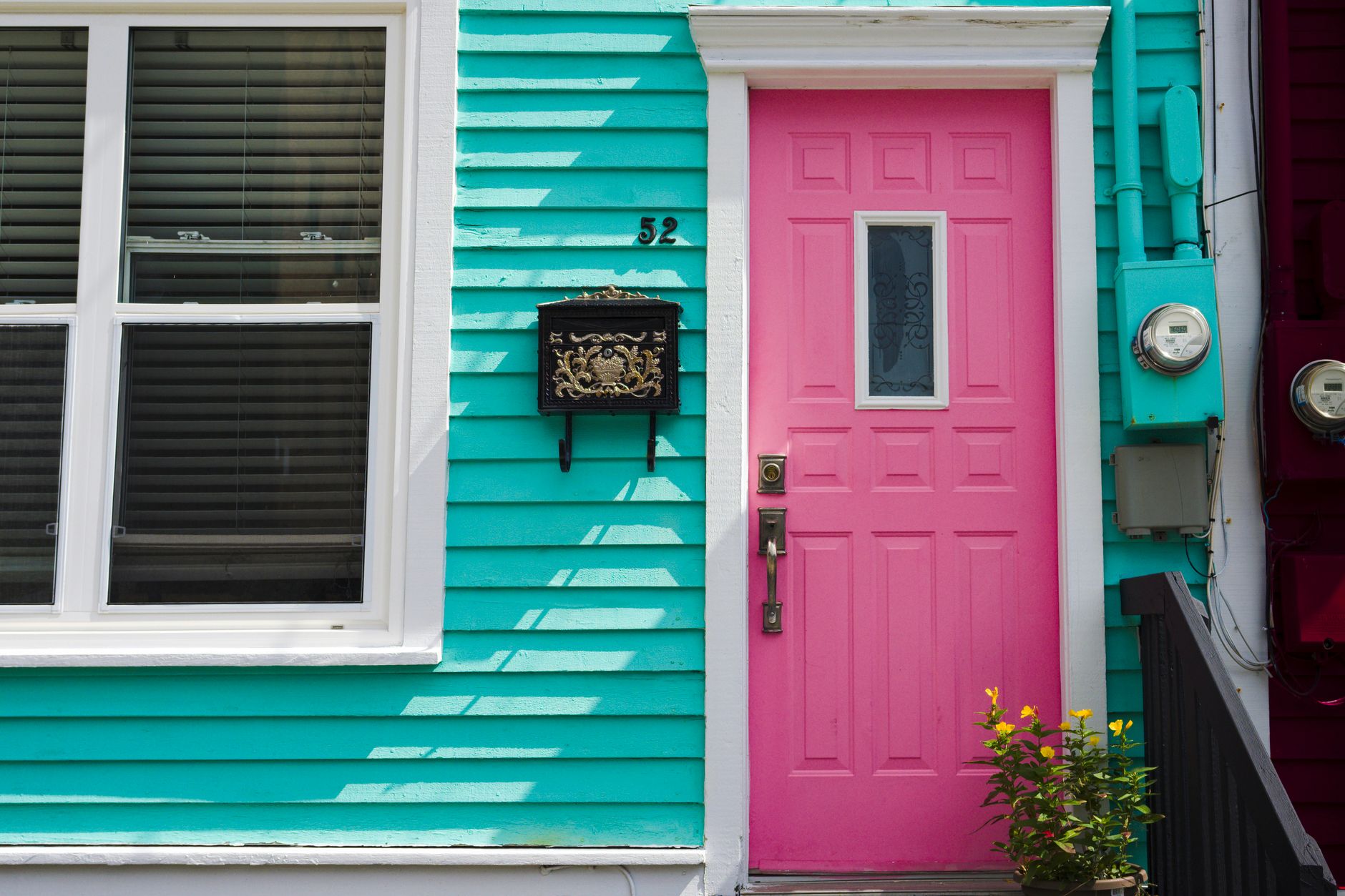 Colorful townhouse exterior with a pink door and teal siding, showing an affordable way to update curb appeal with color