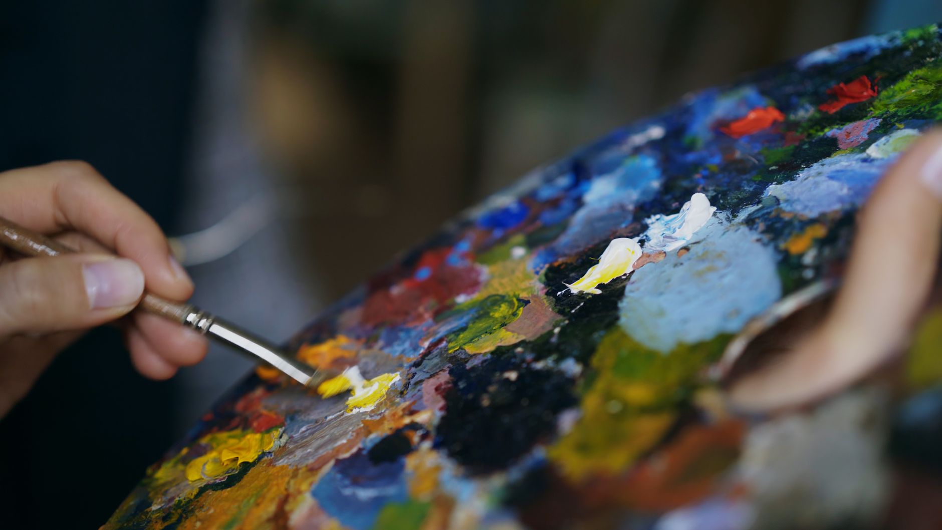 Close-up of a painter mixing colors on a palette, representing the color and paint choices that shape a house painting estimate